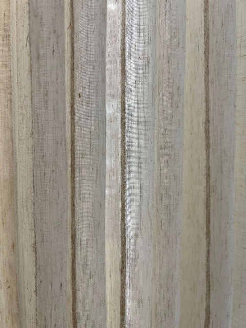 Semi-sheer linen-look drapery fabric close-up with natural woven texture, soft light filtering effect, and neutral beige vertical folds