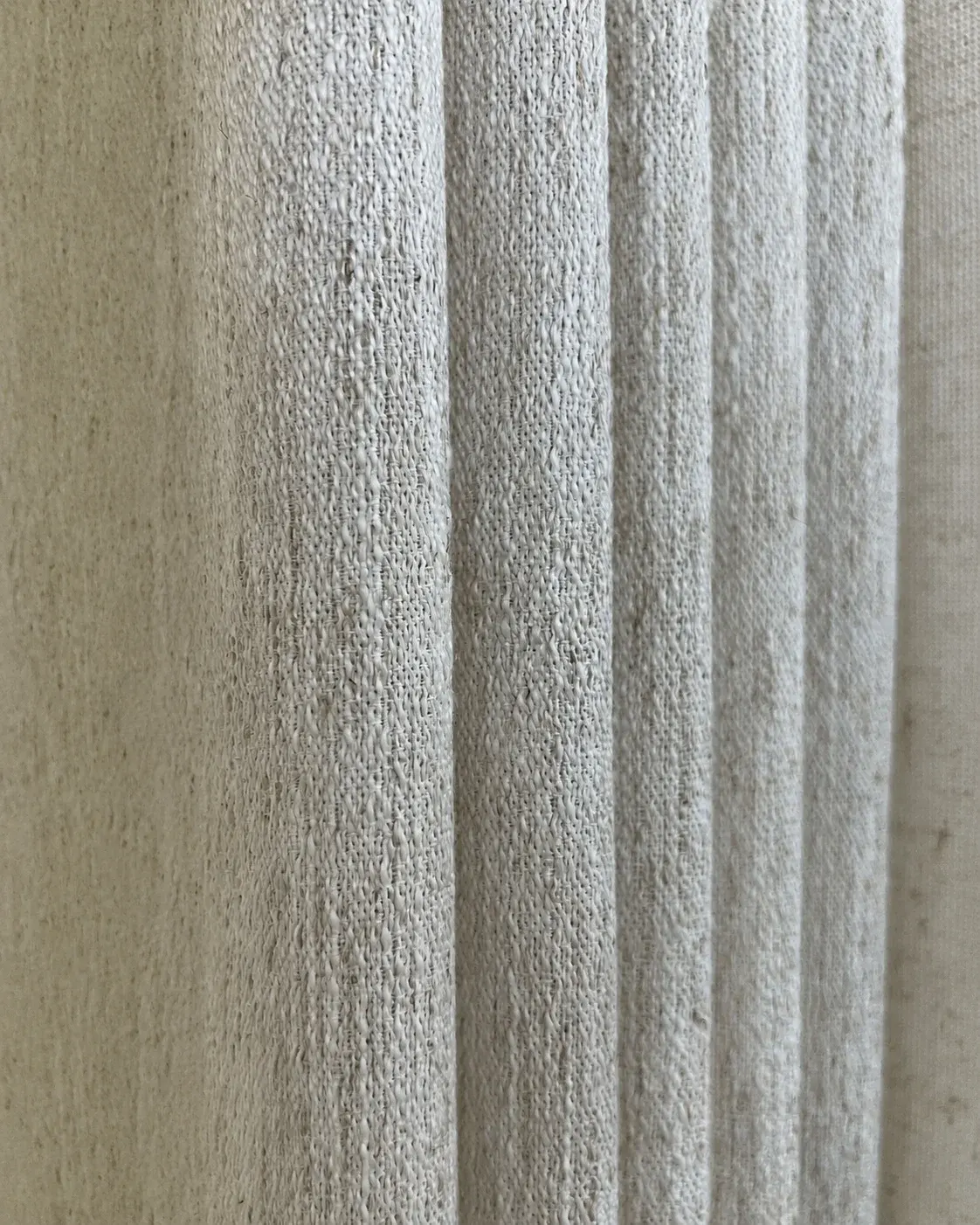 Close-up detail of textured linen-look drapery fabric with soft vertical folds