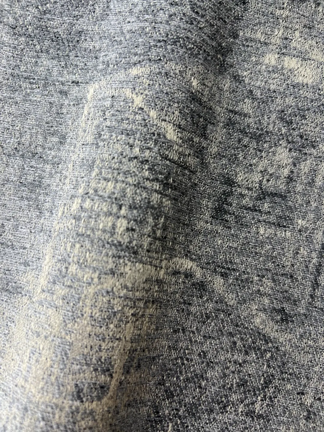 Mottled blue beige textured woven drapery fabric closeup, heavy linen look curtain material